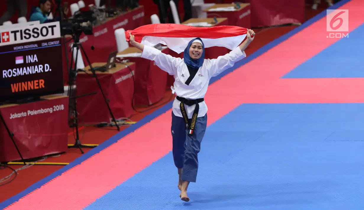 Atlet Taekwondo putri Indonesia, Defia Rosmaniar mengibarkan bendera Merah Putih saat merayakan kemenangan atas Salahshouri Marjan (Iran) pada Final Women Individual Poomsae di JCC, Jakarta, Minggu (19/8). (Liputan6.com/Helmi Fithriansyah)