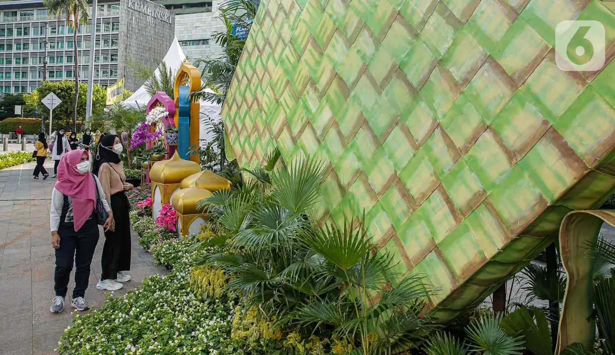 <p>Sejumlah warga memperhatikan dekorasi bertemakan Idul Fitri di kawasan Bundaran HI, Jakarta, Rabu (27/4/2022). Dekorasi berbentuk masjid, ketupat, dan bedug yang dihiasi oleh tanaman tersebut dalam rangka menyambut Idul Fitri 1443 Hijriah. (Liputan6.com/Faizal Fanani)</p>