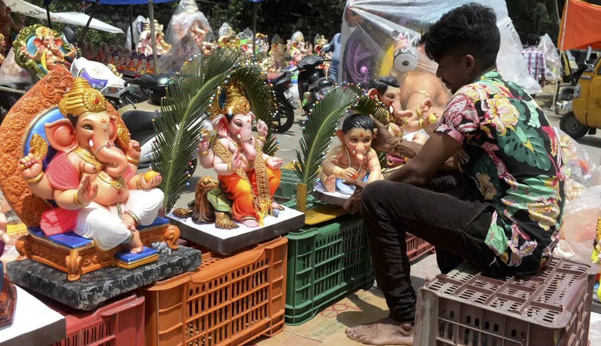 Seorang pekerja memajang patung Dewa Ganesha untuk dijual di kios pinggir jalan di Hyderabad, India, Kamis (9/9/2021). Patung dewa Hindu berkepala gajah tersebut banyak dijual jelang Festival Ganesh Chaturthi. (NOAH SEELAM/AFP)