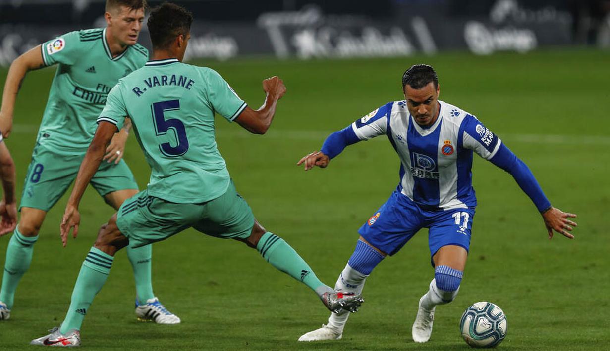 Pemain Espanyol, Raul de Tomas, berusaha melewati pemain Real Madrid, Raphael Varane, pada laga La Liga di Stadion Cornella-El Prat, Minggu (28/6/2020). Real Madrid menang 1-0 atas Espanyol. (AP/Joan Monfort)