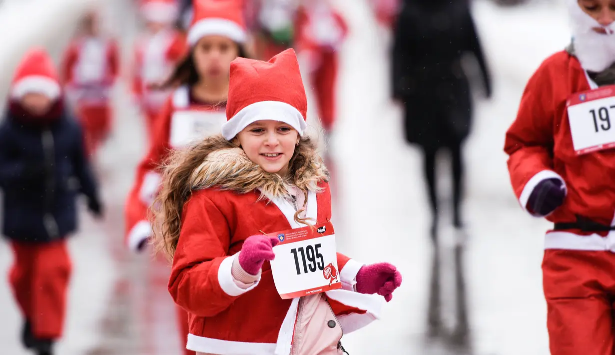 Seorang anak perempuan berpakaian Sinterklas mengambil bagian dalam Santa Claus Run di Pristina, Minggu (16/12). Ratusan pelari berpartisipasi dalam lomba lari amal untuk menggalang dana bagi keluarga yang membutuhkan di Kosovo. (Armend NIMANI/AFP)