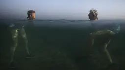 Pengunjung saat berenang di laut Havana, (28/4/2015). Badan dan kepala dari dua orang ini tampak ditempat yang berbeda. (REUTERS/Alexandre Meneghini)