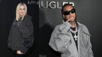 Foto kolase Avril Lavigne dan Tyga saat menghadiri Mugler x Hunter Schafer Party selama acara Paris Fashion Week di Prancis pada Selasa, 7 Maret 2023. Tyga dan Avril melawati banyak kerumunan dengan saling bergandengan tangan. Tampak Tyga mengenakan kemeja dan celana abu-abu dengan kalung-kalung silver besar. Sementara Avril mengenakan hoodie oversized dan boots tinggi ala Ariana Grande. (Scott Garfitt/Invision/AP)