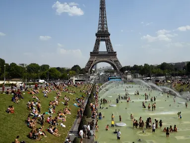 Turis dan warga menyejukkan diri dan berjemur di kolam Trocadero Fountains (air mancur Trocadero) dekat Menara Eiffel di Paris, Kamis (25/7/2019). Gelombang panas di Eropa mencapai puncaknya, bahkan suhu di ibu kota Prancis mencapai di atas 41 derajat Celcius. (Bertrand GUAY / AFP)