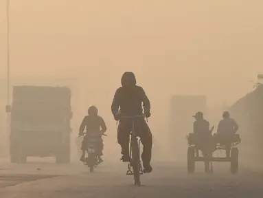 Pengendara melintas di sepanjang jalan di tengah kondisi kabut asap di Lahore, Pakistan (23/11/2021). Kondisi kabut asap yang memburuk membuat Lembaga pendidikan, kantor swasta tutup selama tiga hari seminggu di Lahore. (AFP/Arif Ali)