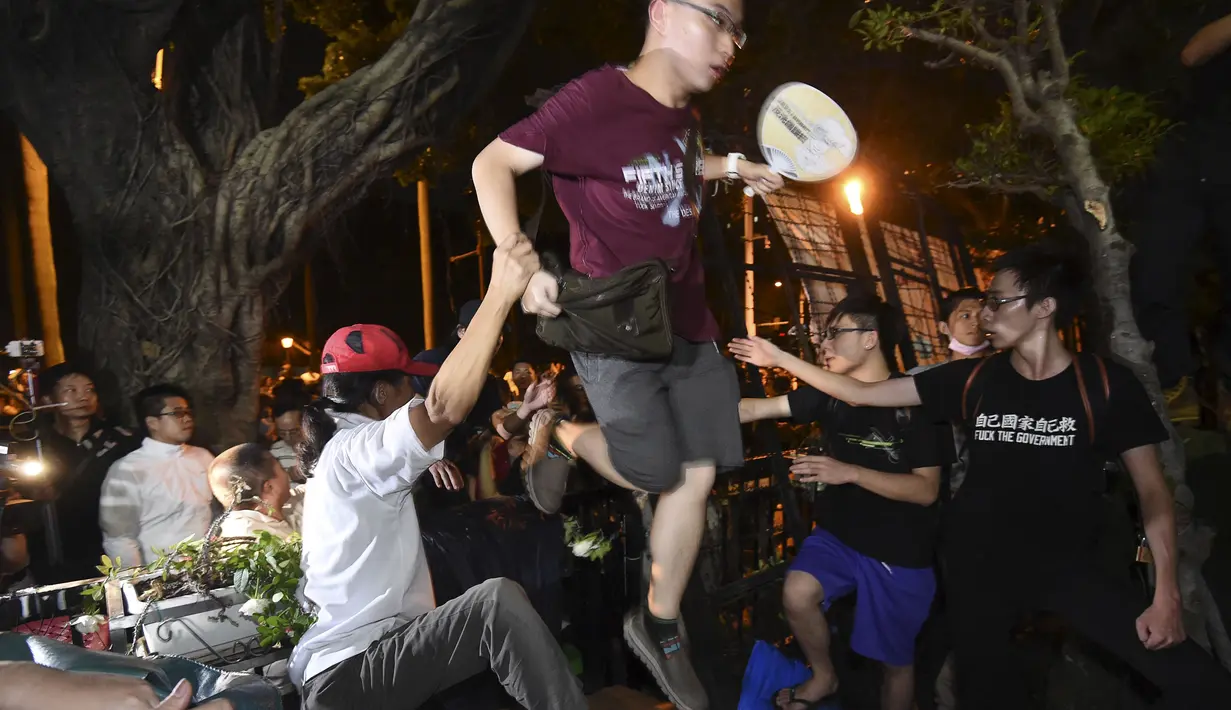 Pelajar nekat menerobos pagar berduri untuk masuk ke Gedung Kementerian Pendidikan,Taipei, Taiwan, Jumat (31/7/2015). Kemarahan mereka dipicu oleh aksi bunuh diri salah satu rekannya di tengah perselisihan buku sekolah "One China". (REUTERS/Pichi Chuang)