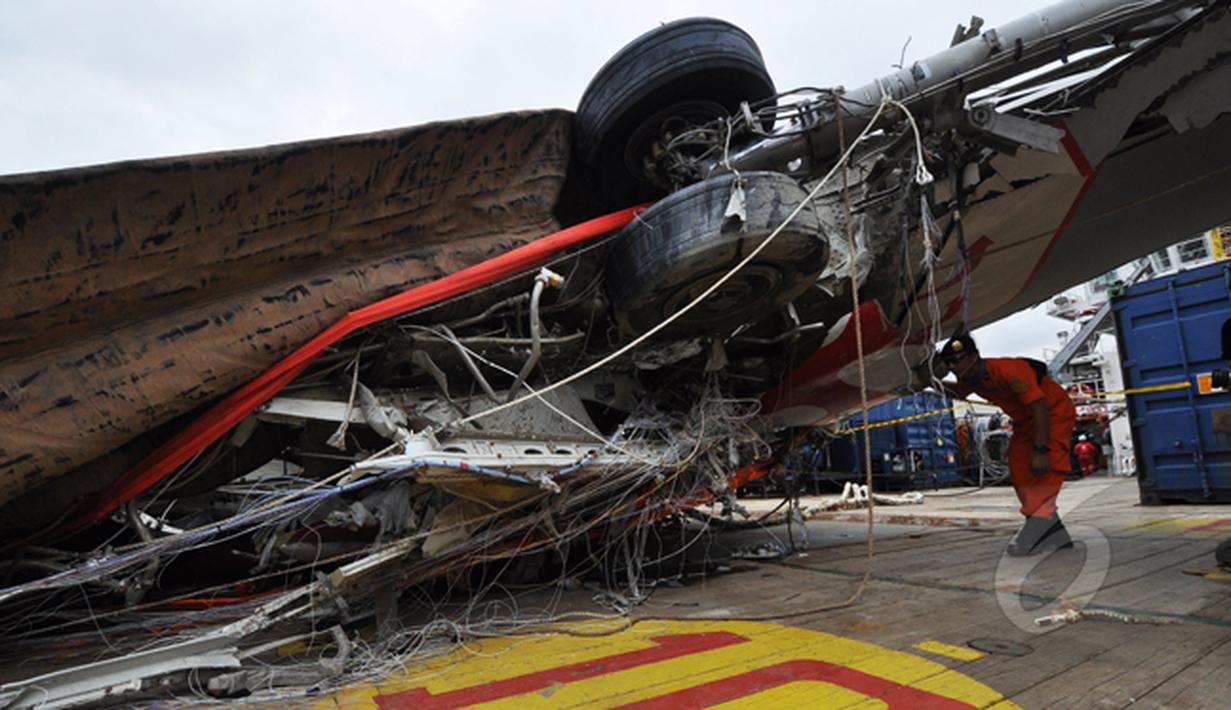 Seorang petugas memperhatikan kondisi bangkai badan pesawat Airasia QZ8501 yang berhasil dievakuasi, Pelabuhan Tanjung Priok, Jakarta, Senin (2/3/2015). (Liputan6.com/Faizal Fanani)