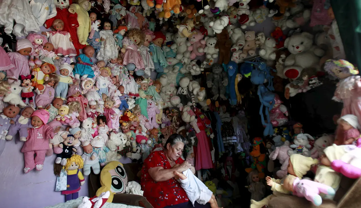 Adela Rojas saat memakaikan pakaian ke boneka miliknya di Heredia, Costa Rica (5/8/2015). Rojas telah mengumpulkan boneka selama lebih dari dua puluh tahun dan sekarang memiliki lebih dari 4.500 boneka. (REUTERS/Juan Carlos Ulate)