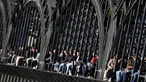 Kaum muda menikmati matahari terbenam di jembatan 'Hackerbruecke' di Munich, Jerman, Minggu, (28/3/2021). Hackerbrücke (Hacker Bridge) adalah jembatan jalan raya yang melintasi jalur kereta api utama di Munich tepat di sebelah barat stasiun pusat kota. (AP Photo/Matthias Schrader)