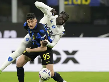 Pemain Inter Milan, Alessandro Bastoni (depan) berebut bola dengan pemain Empoli, Mbaye Niang pada laga lanjutan Liga Italia 2023/2024 yang berlangsung di Stadion Giuseppe Meazza, Milan, Italia, Selasa (02/04/2024) WIB. (AP Photo/Antonio Calanni)