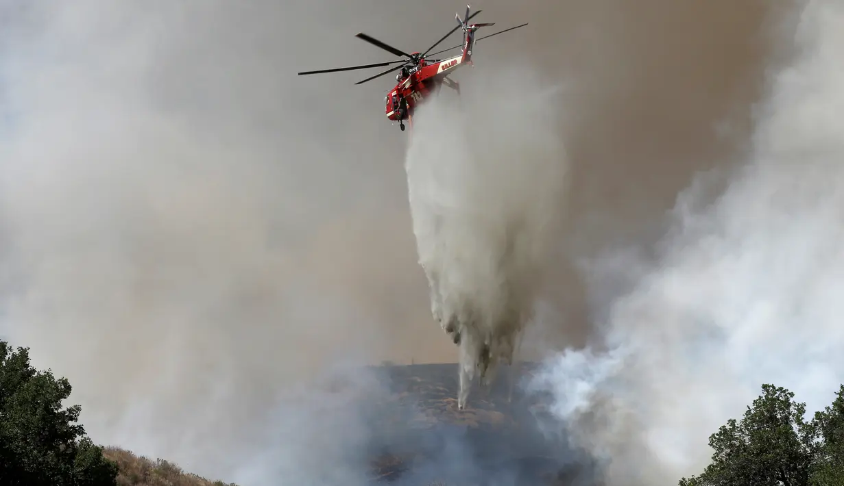 Helikopter membantu memadamkan api yang melanda Hutan Nasional Angeles dekat Los Angeles, California, AS (24/7). Setidaknya terdapat 300 orang yang telah dievakuasi oleh pihak berwenang ke tempat yang lebih aman, di luar kota. (REUTERS / Jonathan Alcorn)