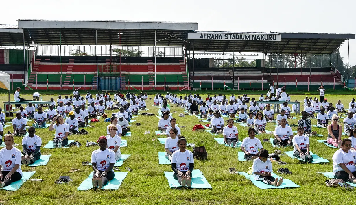 Ratusan warga melakukan gerakan yoga saat mengikuti yoga massal di Stadion Afraha, Nakuru, Kenya (15/6/2019). Hari Yoga Internasional, yang setiap tahun dirayakan pada 21 Juni, pertama kali diusulkan Perdana Menteri India Narendra Modi pada 2014 ke Majelis Umum PBB. (AFP Photo/Suleiman Mbatiah)