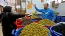 Warga membeli buah zaitun untuk persiapan menyambut datangnya bulan Ramadan di Ibu Kota Tripoli, Libya, 1 Mei 2019. Ramadan kali ini diperkirakan akan terasa berat bagi warga Tripoli karena bayang-bayang krisis dan pertempuran. (MAHMUD TURKIA/AFP)