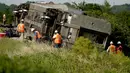 Pekerja memeriksa lokasi kereta Amtrak yang tergelincir setelah menabrak truk sampah di dekat Mendon, Missouri, AS (27/6/2022). Peristiwa itu terjadi sehari setelah kereta lain yang dioperasikan Amtrak bertabrakan dengan kendaraan penumpang di perlintasan kereta api di California, yang mengakibatkan tiga kematian. (AP Photo/Charlie Riedel)