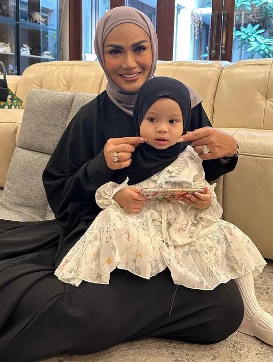 Krisdayanti dalam kesempatan lainnya terlihat memangku Ameena yang tampil gemas dalam balutan dress putih dan hijab hitam. Krisdayanti sendiri tampil dengan abaya hitam dan hijab cokelat. [Foto: Instagram/krisdayantilemos]