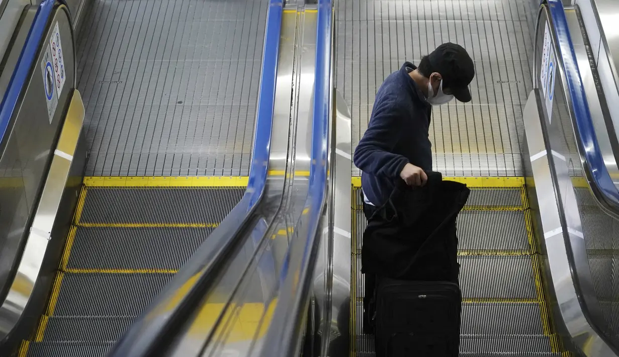 Seorang pria yang mengenakan masker tuk membantu mencegah penyebaran virus corona naik lift di Tokyo, Selasa (6/4/2021). Ibukota Jepang mengonfirmasi lebih dari 390 kasus virus korona baru pada hari Selasa. (AP Photo/Eugene Hoshiko)