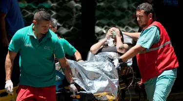 Seorang wanita dibawa ke ambulans setelah dievakuasi dari gedung perkantoran yang terbakar di pusat kota Buenos Aires, Argentina, Selasa (12/12/2023). (AP Photo/Natacha Pisarenko)