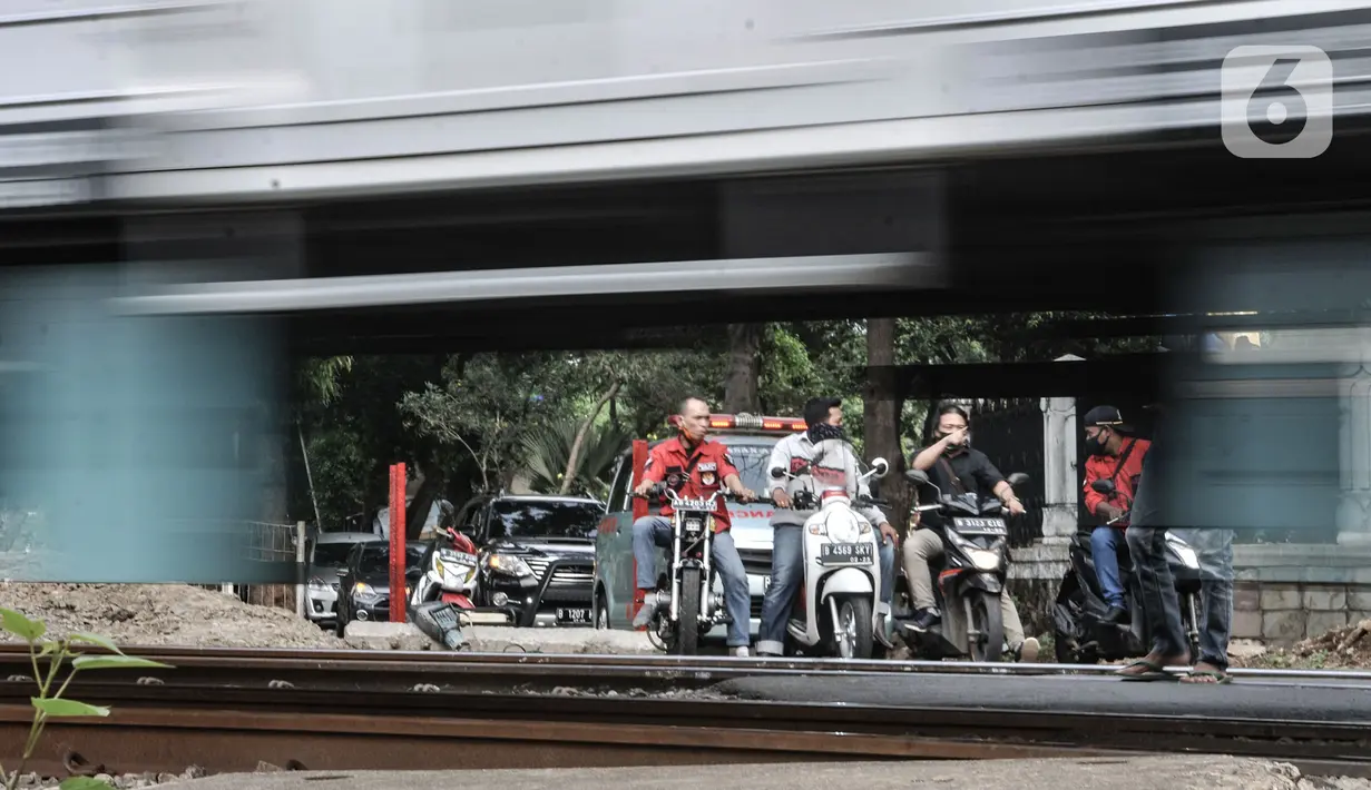 Pengendara motor menunggu kereta melintas saat akan melewati perlintasan sebidang tanpa palang pintu di kawasan TPU Tanah Kusir, Jakarta, Kamis (17/9/2020). Sebelumnya pada Kamis (17/9) pagi terjadi kecelakaan sebuah mobil dan KRL di perlintasan tersebut. (merdeka.com/Iqbal S. Nugroho)
