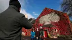 Wisatawan berpose di dekat Blair Athol Distillery, Skotlandia, Selasa (18/10). Blair Athol Distillery adalah kawasan objek wisata dengan bangunan unik karena ditumbuhi tumbuhan merambat berwarna merah.( REUTERS / Russell Cheyne)