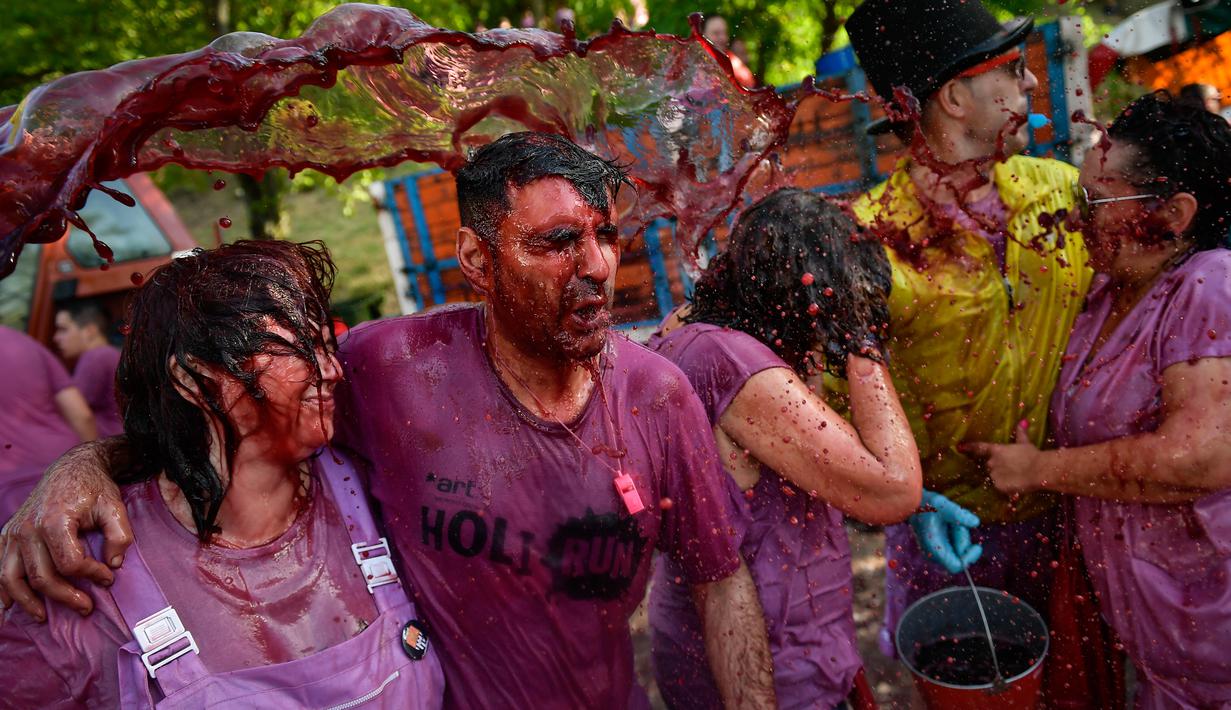 Peserta diguyur anggur merah saat ambil bagian dalam perang anggur di Haro, Spanyol utara, Sabtu (29/6/2019). Setiap peserta wajib mengenakan pakaian putih pada festival yang diselenggarakan rutin setiap bulan Juni di kota Haro, yang terkenal sebagai produsen anggur tersebut. (AP/Alvaro Barrientos)