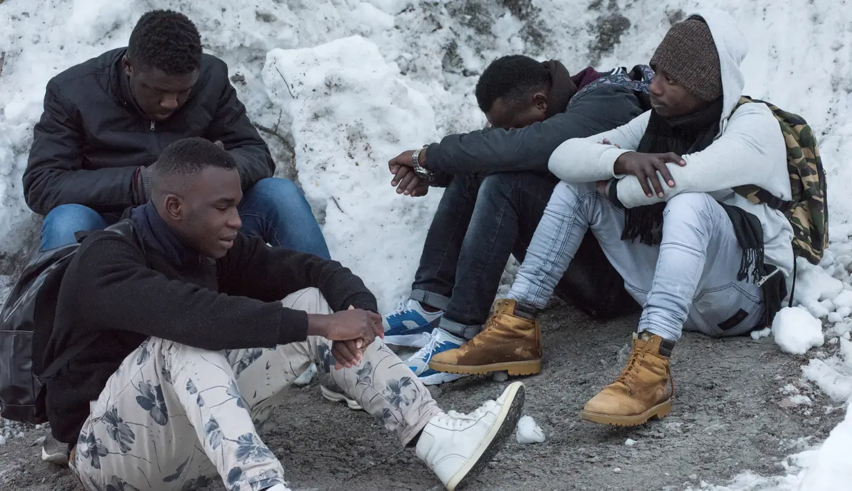 Imigran dari Mali dan Burikna Faso beristirahat dalam perjalanan menuju Colle della Scala (Col de l'Echelle) untuk melewati perbatasan antara Italia dan Prancis di Pegunungan Alpen, Italia (13/1). (AFP/Piero Cruciatti)