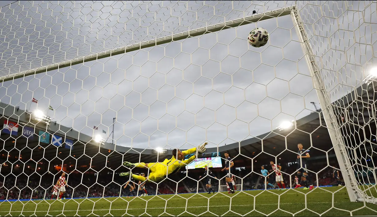 Pemain Kroasia Luka Modric mencetak gol ke gawang Skotlandia yang dijaga David Marshall pada pertandingan Grup D Euro 2020 di Stadion Hampden Park, Glasgow, Selasa (22/6/2021). Kroasia menang 3-1. (AP Photo/Petr David Josek, Pool)