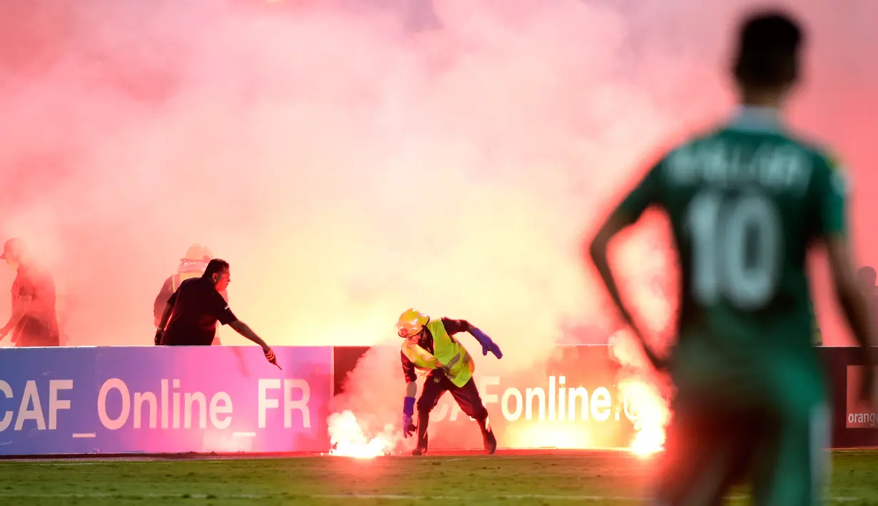 Petugas berusaha mengambil suar saat pertandingan antara klub Mesir, Zamalek dan klub Libya, Al Ahly Tripoli pada lanjutan Grup B Liga Champion Afrika di Army Stadium, Alexandria, Mesir, (9/7). (AFP Photo/Khaled Desouki)