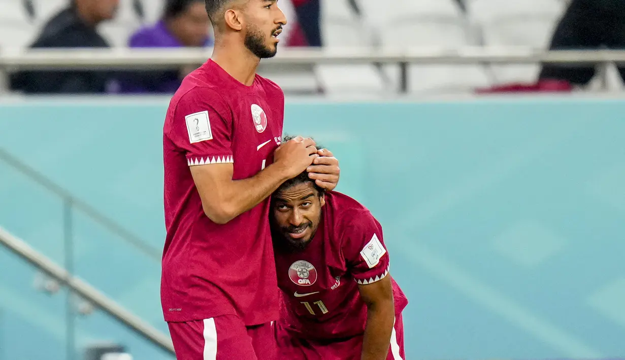 Gelandang Qatar, Mohammed Waad memeluk rekan setimnya Akram Afif setelah kalah 1-3 dari Senegal dalam pertandingan grup A Piala Dunia di Stadion Al Thumama di Doha, Qatar, Jumat, 25 November 2022. 'The Maroon' juga jadi tuan rumah pertama dalam sejarah Piala Dunia yang tereliminasi usai main dua laga. (AP Photo/Petr Josek)