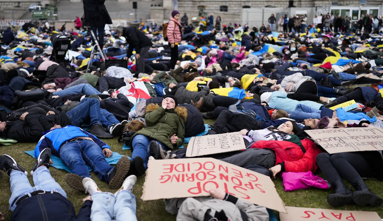 Orang-orang berbaring di tanah melambangkan mereka yang tewas dalam perang di Ukraina selama demonstrasi menentang invasi Rusia, dekat gedung parlemen Jerman, di Berlin, 6 April 2022. Pengunjuk rasa menuntut Berlin berhenti membeli minyak dan gas Rusia. (AP Photo/Markus Schreiber)