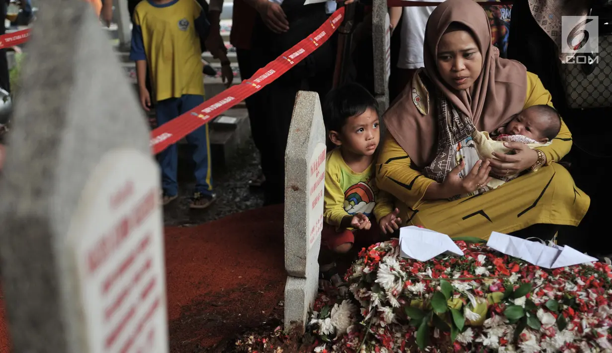Seorang ibu sambil menggendong bayinya berziarah ke makam Presiden ketiga RI BJ Habibie di TMP Kalibata, Jakarta, Kamis (12/9/2019). Hingga sore hari, warga terus berdatangan ke TMP kalibata untuk dapat berkesempatan mendoakan almarhum BJ Habibie. (merdeka.com/Iqbal Nugroho)