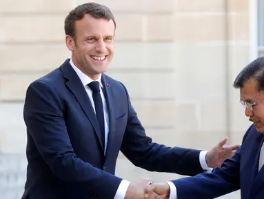 Presiden Prancis Emmanuel Macron (kiri) menyalami Wakil Presiden Indonesia Jusuf Kalla saat menghadiri KTT Paris: Ekstremisme Online di Istana Elysee, Paris, Prancis, Rabu (15/5/2019). Presiden Macron terlihat hangat saat menyambut Wapres Kalla. (REUTERS/Philippe Wojazer)