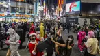 Para pejalan kaki dengan kostum berpose untuk foto ketika ribuan orang berkumpul di distrik Shibuya, area pertemuan populer untuk Halloween, di Tokyo, Minggu (31/10/2021). Daerah di sekitar Stasiun Shibuya dipadati anak-anak muda yang berdandan selama Halloween setiap tahun. (AP Photo/Kiichiro Sato)