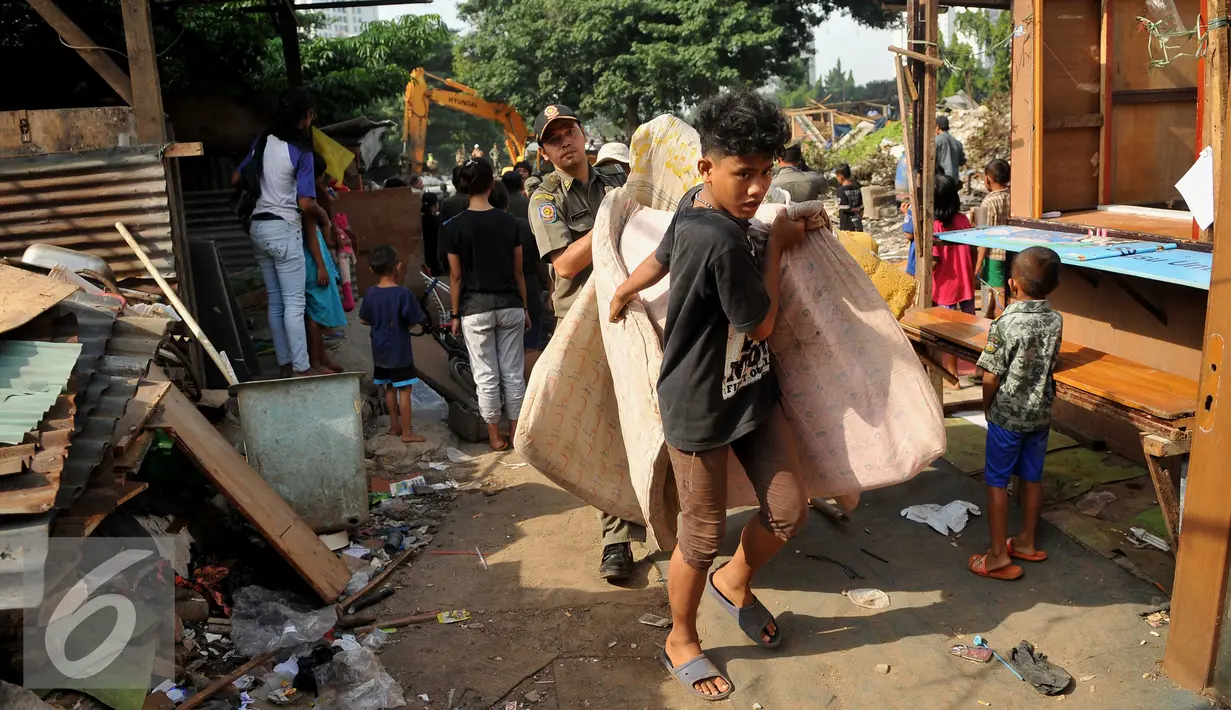 Warga dibantu petugas mengevakuasi barang saat penggusuran di kawasan TPU Menteng Pulo, Jakarta Selatan (7/4). Lebih dari seratus kepala keluarga digusur karena menempati lahan dan mendirikan bangunan di pemakaman umum. (Liputan6.com/Gempur M Surya)