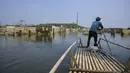Seorang pria mengendalikan rakit bambunya di kawasan Bendungan Karian yang mengering di Kampung Somang, Lebak, Banten, Kamis (30/7/2026). (AFP/ Bay Ismoyo)