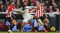 Pemain Real Madrid, Jude Bellingham berebut bola dengan pemain Athletic Bilbao, Mikel Jauregizar (kanan) dan Yeray Alvarez (kiri) pada laga lanjutan Liga Spanyol 2024/2025 di San Mames Stadium, Bilbao, Spanyol, Kamis (05/12/2024) dini hari WIB. (AP Photo/Miguel Oses)