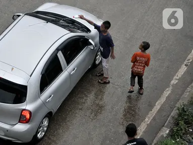 Seorang anak membersihkan kaca mobil yang melintas di Jalan Raya Bekasi, Cakung, Jakarta, Selasa (17/3/2020). Akibat keterbatasan ekonomi, anak-anak yang masih duduk di bangku sekolah dasar ini nekat menawarkan jasa membersihkan kaca mobil dan truk di jalan raya. (merdeka.com/Iqbal S Nugroho)