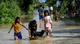 Anak-anak bermain di air banjir setelah hujan lebat di Phnom Penh, Kamboja (26/10/2021). Kementerian Sumber Daya Air dan Meteorologi telah mengeluarkan pemberitahuan pada hari Senin tentang situasi cuaca, mengkonfirmasikan risiko banjir di 14 ibu kota dan provinsi Kamboja. (AFP/Tang Chhin Sothy)