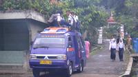 Tiap pagi, sebagian anak sekolah naik di atas atap kendaraan dari Citepus ke Jeruklegi, Cilacap, lantaran tak kebagian tempat duduk. (Foto: Liputan6.com/Muhamad Ridlo)
