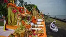 Seorang umat Hindu mempersiapkan persembahan untuk sembahyang selama upacara ritual Melasti di Pantai Arafuru, Surabaya, 23 Maret 2025. (JUNI KRISWANTO/AFP)