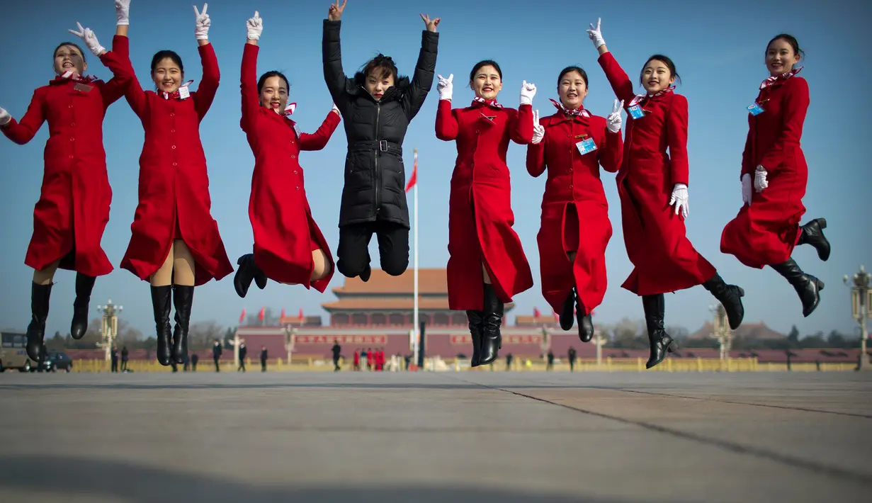Sejumlah wanita berpose dengan latar belakang Istana Kuno Dinasti Ming dan Qing saat menyambut peserta Kongres Rakyat Nasional di Beijing, China, Senin (4/3). Kongres ini digelar setiap tahun. (AP Photo/Mark Schiefelbein)