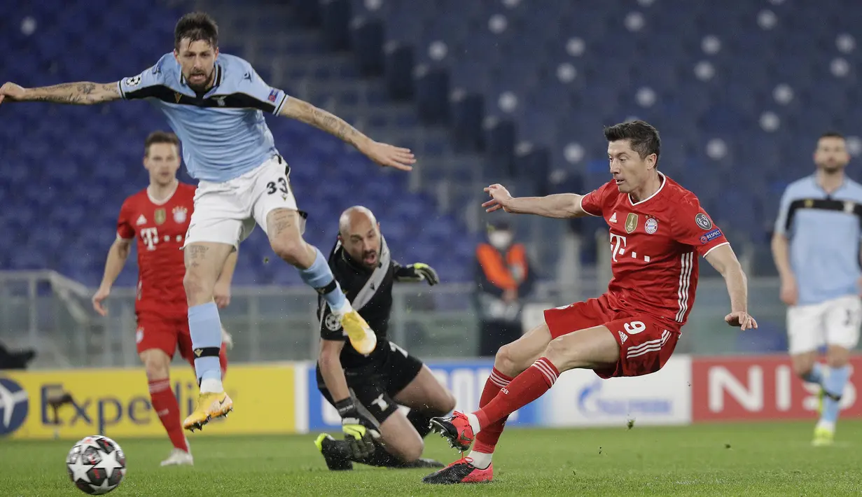 Striker Bayern Munich, Robert Lewandowski (kanan) melepaskan tendangan yang berbuah gol pertama timnya ke gawang Lazio dalam laga leg pertama babak 16 besar Liga Champions 2020/21 di Olimpico Stadium, Selasa (23/2/2021). Bayern Munich menang 4-1 atas Lazio. (AP/Gregorio Borgia)
