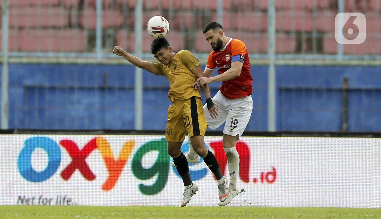 Pemain Borneo FC Samarinda Javlon Guseynov berebut bola dengan pemain Bhayangkara Solo FC Dendy Sulistyawan (kiri) dalam pertandingan babak penyisihan Piala Menpora 2021 di Stadion Kanjuruhan, Malang, Jawa Timur, Senin (22/3/2021). (Bola.com/Arief Bagus)