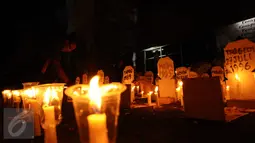 Aktivis menyalakan lilin diantara replika nisan korban pelanggaran HAM masa lalu saat peringatan 19 tahun reformasi di Galeri Cipta 2 TIM, Jakarta, Jumat (12/5). Aksi ini diikuti puluhan aktivis. (Liputan6.com/Helmi Fithriansyah)