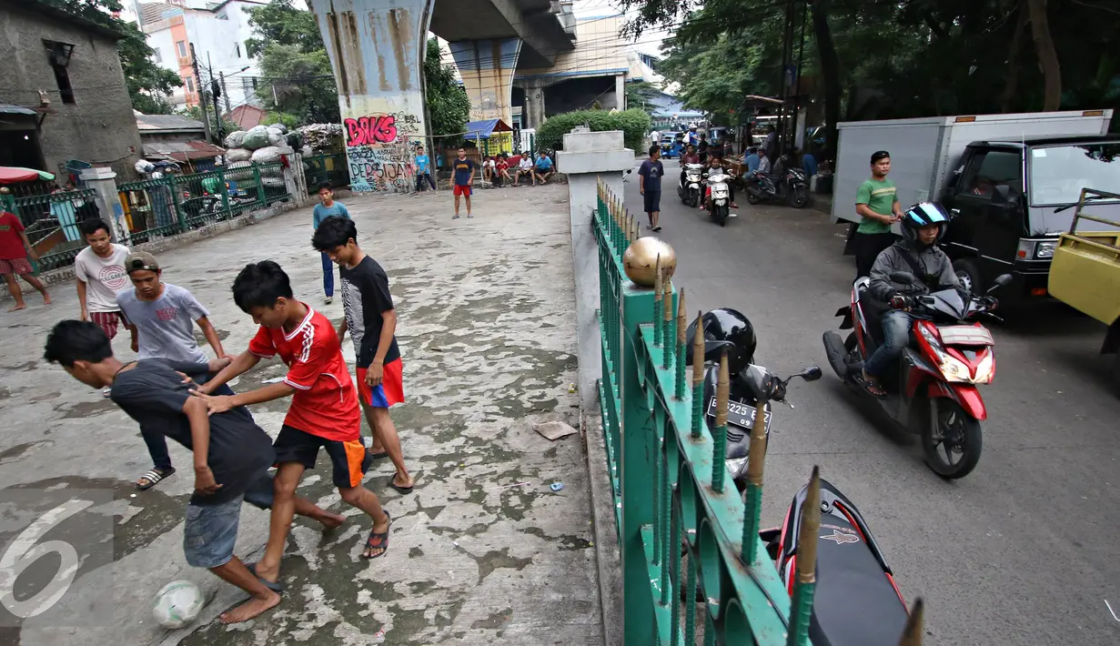 Sejumlah remaja berebut bola saat bermain di kolong rel kereta kawasan Juanda, Jakarta, Jumat (27/5). Tidak tersedianya ruang terbuka menyebabkan lahan tersebut dijadikan tempat bersosialisasi bagi warga. (Liputan6.com/Immanuel Antonius)