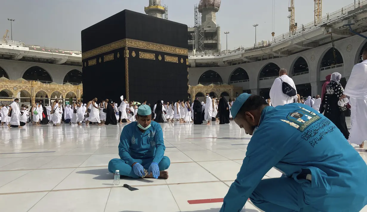 Pekerja menghapus tanda-tanda jarak sosial di Masjidil Haram di kota suci Muslim Mekkah, Arab Saudi, Minggu (6/3/2022). Arab Saudi mengambil kebijakan untuk mengakhiri semua pembatasan Covid-19 termasuk kebijakan jaga jarak dan menggunakan masker di luar ruangan. (AP Photo/Amr Nabil)