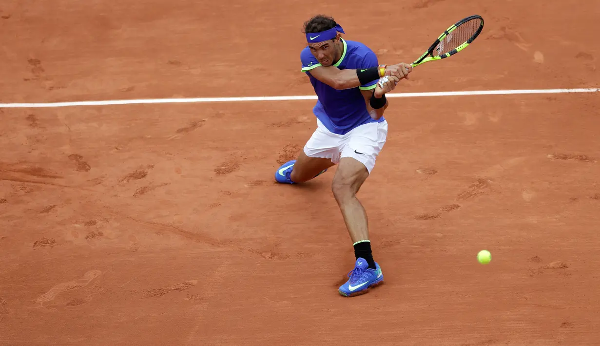Petenis Spanyol, Rafael Nadal mengembalikan bola ke arah lawannya petenis Prancis, Benoit Paire pada babak pertama Prancis Terbuka  di Stade Roland Garros, Senin (29/5). Nadal mengalahkan tuan rumah dengan skor 6-1, 6-4, 6-1. (AP Photo/Petr David Josek)
