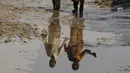 Seorang anak laki-laki dan perempuan tercermin dalam air di dekat rumah mereka yang dilanda banjir, di Charsadda, Pakistan, Rabu (31/8/2022). Para pejabat di Pakistan menyampaikan kekhawatiran Rabu atas penyebaran penyakit yang ditularkan melalui air di antara ribuan korban banjir saat air banjir dari hujan monsun yang kuat mulai surut di banyak bagian negara. (AP Photo/Mohammad Sajjad)