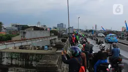 Sejumlah pengendara menepi untuk melihat kondisi kali Ciliwung dan beberapa anak melakukan aksi lompat dari atas jembatan Ciliwung Kalibata, Jakarta, Selasa (25/2/2020). (merdeka.com/magang/Muhammad Fayyadh)