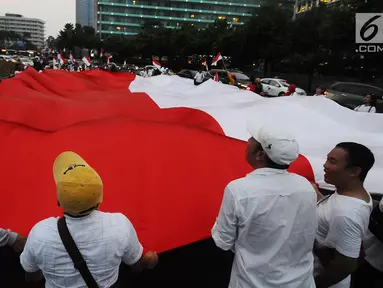 Sejumlah pendukung capres-cawapres 01 Jokowi-Ma'ruf Amin membentangkan bendera merah putih di kawasan bunderan HI, Jakarta, Rabu (17/4). Pendukung capres-cawapres 01 arak-arakan merayakan unggul dalam versi hitungan cepat. (Liputan6.com/Herman Zakharia)