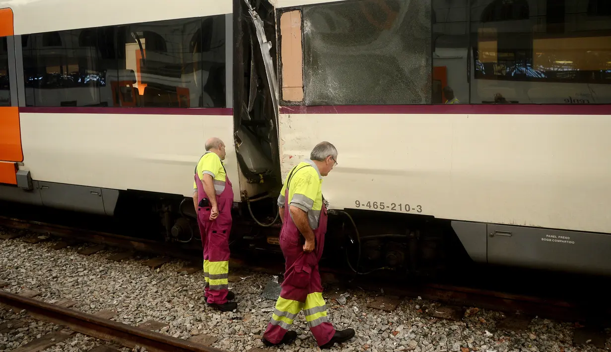Pekerja melihat kondisi kereta yang rusak di platform sebuah stasiun kereta api di Barcelona, Spanyol, Jumat, (28/7). Puluhan orang terluka saat sebuah kereta komuter pagi yang mereka tumpangi menabrak buffer. (AP Photo/Adrian Quiroga)